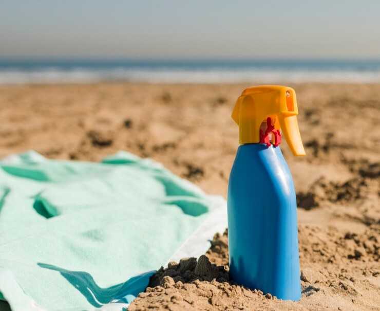 Serviette et crème solaire posés sur la plage au bord de la mer