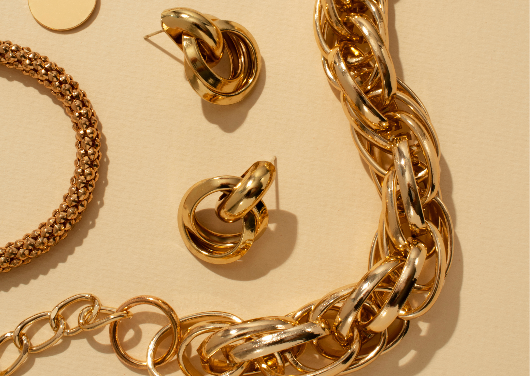 Chaine et boucles d'oreille dorées posées à plat